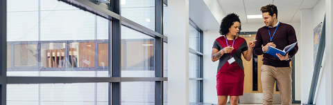 Professionals talking while walking down a hallway looking at a report.